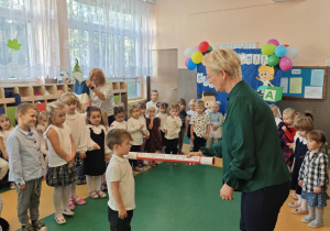 Pani dotyka ramienia chłopca dużym ołówikem