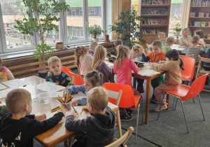 Biblioteka - dzieci siedzą przy trzech stolikach i kolorują świąteczne obrazki