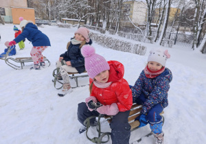 Trzy dziewczynki na górce jadące na sankach