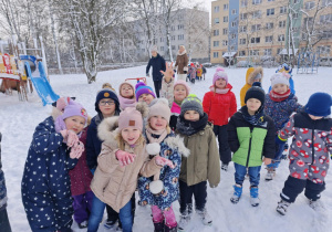 Dzieci bawiące się na śniegu w ogrodzie przedszkolnym