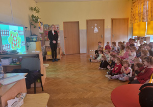 Grupa dzieci ogląda prezentację na temat bezpiecznego przechodzenia przez tory kolejowe.