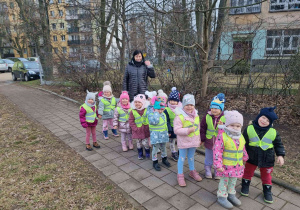 Grupa dzieci podczas spaceru obok przedszkola.