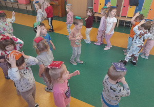Dzieci wykonują ćwiczenia z woreczkami na sali gimnastycznej.