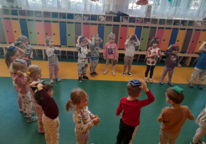 Dzieci wykonują ćwiczenia z woreczkami na sali gimnastycznej.