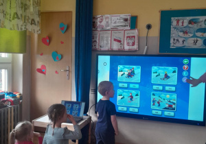 Chłopiec dopasowuje elementy wyświetlane na ekranie multimedialnym.