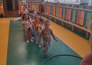 Dzieci ustawione w rzędzie celują woreczkiem do koła.