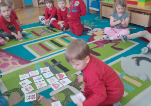 Chłopiec układa serduszka według wzoru na dywanie.
