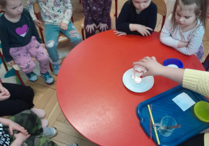 Dzieci oglądają doświadczenie ze świeczką i szklanką.