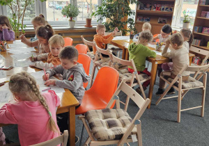 Biblioteka - dzieci siedzą przy stolikach i kolorują obrazki