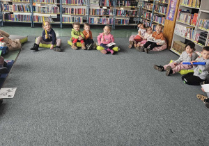 Biblioteka - dzieci siedzą na dywanie z kolorowymi bibułami oznaczającymi pory roku