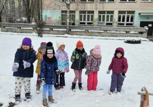 Dzieci w ogrodzie przedszkolnym robią kulki ze śniegu