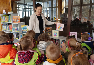 Wizyta w bibliotece - pani bibliotekarka oprowadza dzieci.