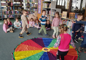 Zajęcia w bibliotece - dzieci bawią sie z chustą animacyjną.