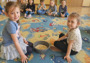 Dzień Świadomości Autyzmu - dzieci siedzą w kole, dwoje dzieci siedzi obok miski z fasolą i pochowanymi w niej kulkami
