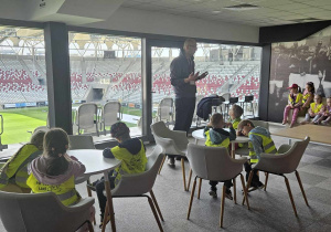 Wycieczka na stadion - dzieci siedzą w loży prezydenckiej i słuchają prowadzącego