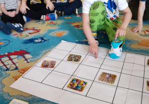 Wielkanocne kodowanie - chlopiec siedzi na dywanie przy macie do kodowania i programuje robota