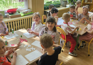 Święto Flagi - dzieci siedzą przy stolikach i wykonują flagi