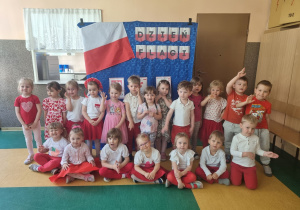 Dzieci ubrane w barwy biało czerwone pozują do zdjęcia w dzień flagi.