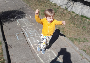 Chłopiec skacze podczas gry w klasy.