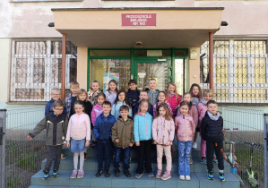 Grupa dzieci pozuje do zdjęcia na schodach przedszkola