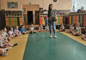 Zabawy ruchowe - dzieci siedzą w kole, prowadząca zapoznaje dzieci z różnymi rodzajami piłek
