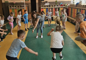 Zabawy ruchowe - dzieci stoją w kole i przeskakują przez myszkę kręcącą przez prowadzącą