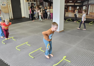Lekcja sportowa w japońskim DOJO - dzieci ustawione w dwa rzędy pokonują tor przeszkód