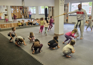 Lekcja sportowa w japońskim DOJO - dziewczynki bawią się w berka, kucają i biegają po sali