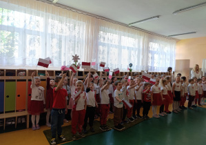 Dzieci ubrane w barwy narodowe śpiewają piosenkę unosząc do góry własnoręcznie wykonane flagi