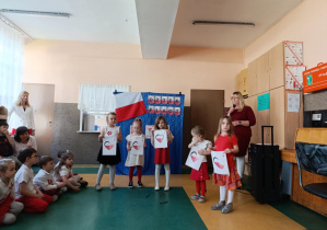 Dziewczynki prezentują karty z biało - czerwonymi sercami