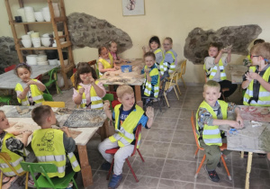 Wycieczka do Michałówki - dzieci siedzą przy stolikach i lepią z gliny