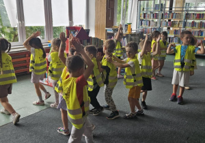 Zajęcia w bibliotece - dzieci idą w trzech pociągach i klaszczą nad głowami