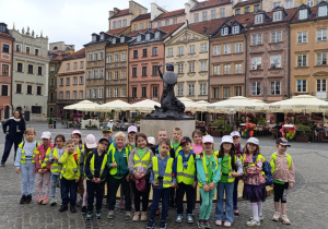 Dzieci pozują do zdjęcia na tle pomnika Syrenki Warszawskiej na rynku Starego Miasta w Warszawie