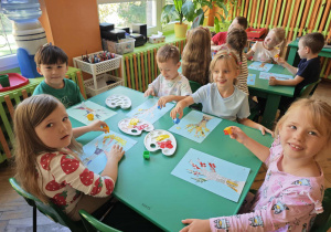 Dzieci stemplują na kartkach czerwoną i żółtą farbą