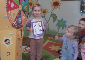 Dziewczynka uśmiechnięta pokazuje wybraną zagadkę.