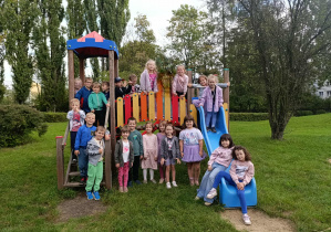 Grupa dzieci pozuje do zdjęcia w ogrodzie przedszkolnym