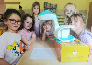 Dziewczynki siedzą przy stoliku i rysują psa przy pomocy projektora