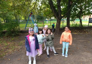 Dziewczynki pozują do zdjęcia w ogrodzie przedszkolnym - pokazują kasztany