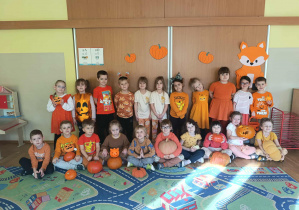 Dzieci ubrane na pomarańczowo pozują do zdjęcia