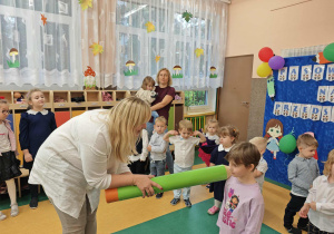 Pani kładzie dziewczynce dużą kredkę na ramieniu