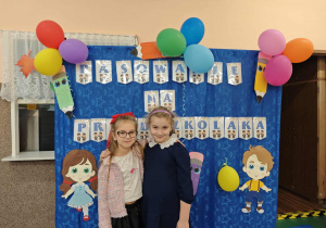 Dwie dziewczynki na tle napisu pasowanie na przedszkolaka