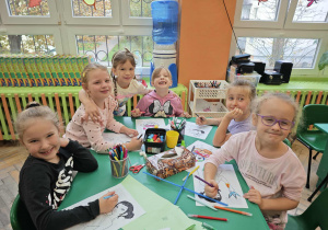 Dziwczynki siedzące przy stole kolorują malowanki
