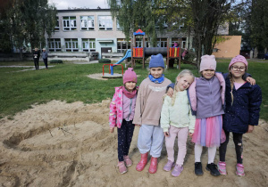 Pięć dziewczynek obejmuje się pozuje do zdjęcia w ogrodzie przedszkolnym