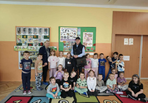 Grupa dzieci wraz z dwoma pracownikami poczty polskiej