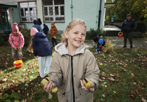 Dziewczynka trzyma w rękach kasztany w łupinach