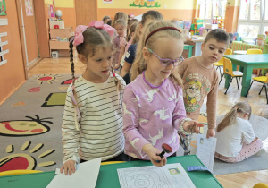 Dzieci stawiają pieczątkę na dużej kartce pocztowej