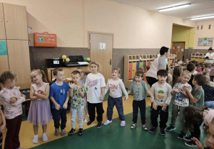 Dzieci stoją w półkolu i trzymają się za ręce
