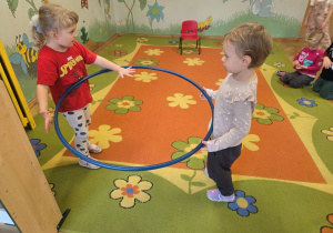 Dwoje dzieci przechodzi z hula-hop.