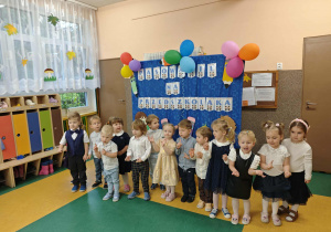 Dzieci stojące na tle napisu pasowanie na przedszkolaka