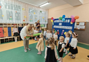 Pani z dużą kredką pośród gromadki dzieci